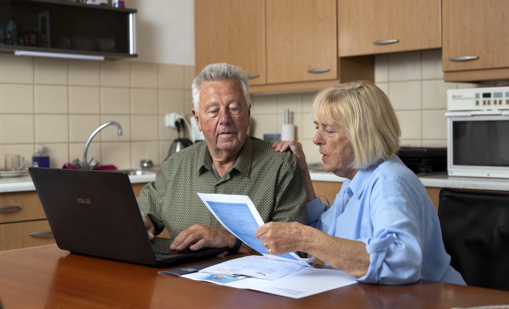 Oudere dame en heer aan tafel met laptop en documenten